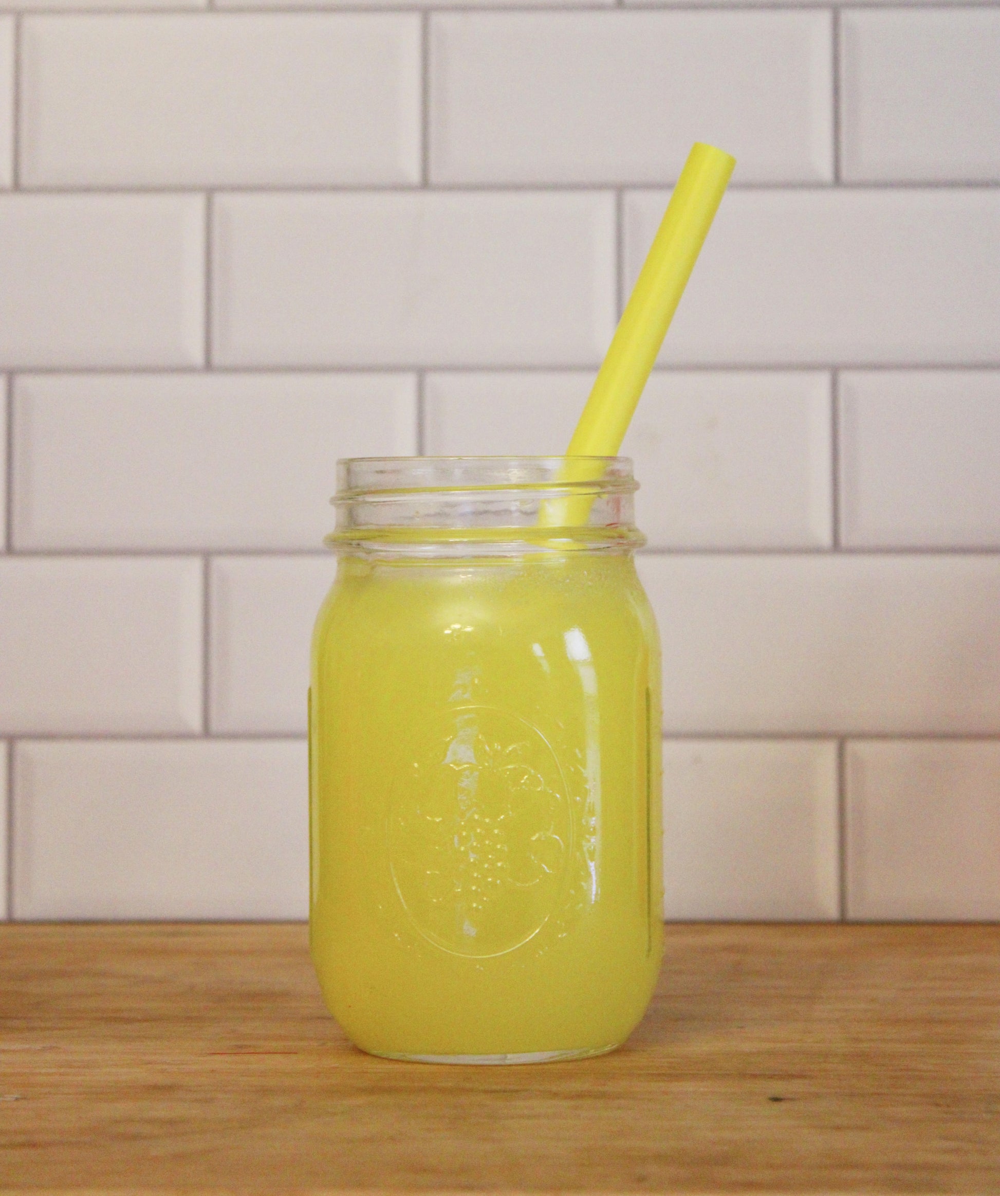 A mason jar with lemonade and a matching yellow straw